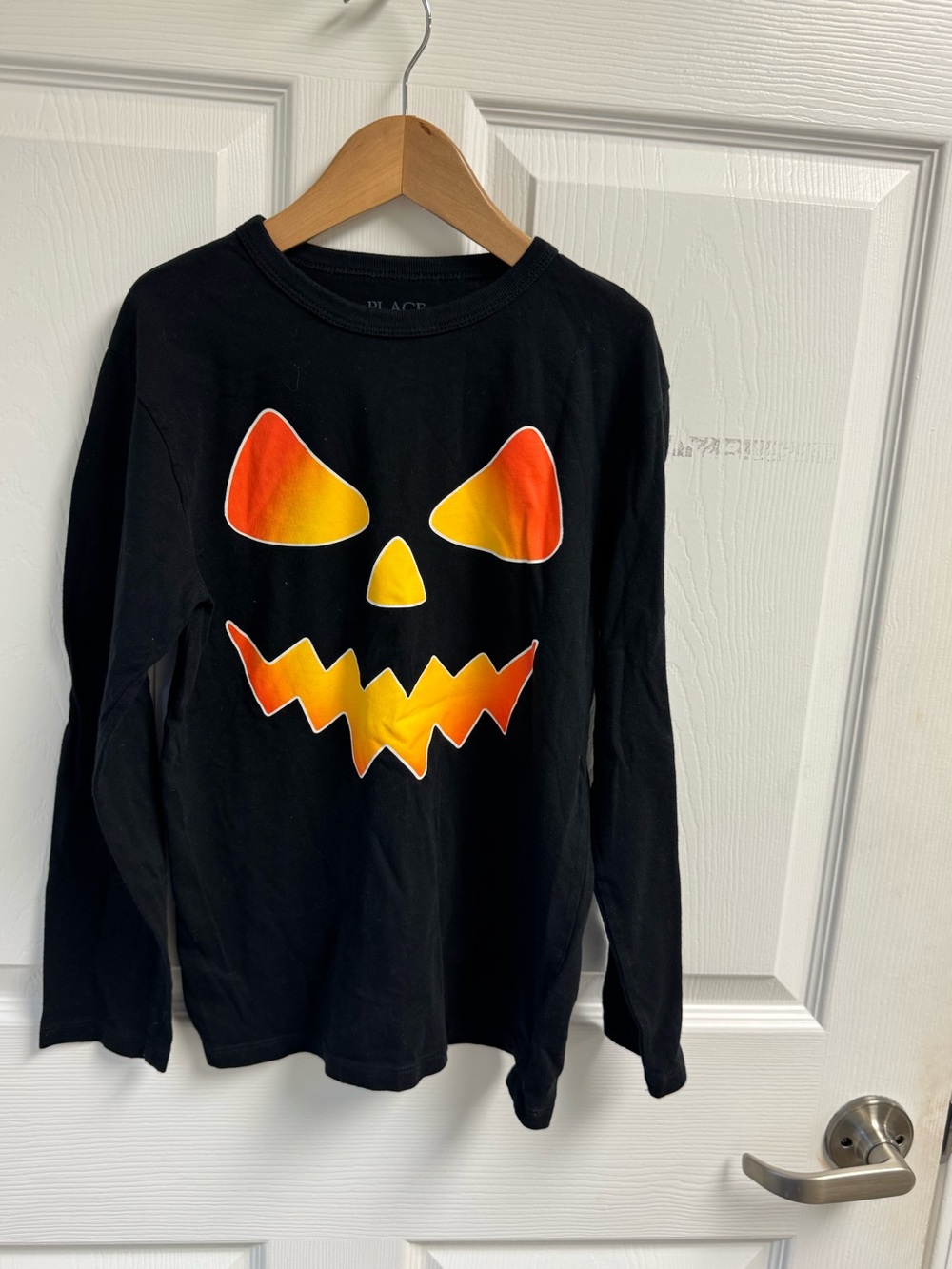Place Black Long Sleeve Top with Orange-Yellow Pumpkin Face
